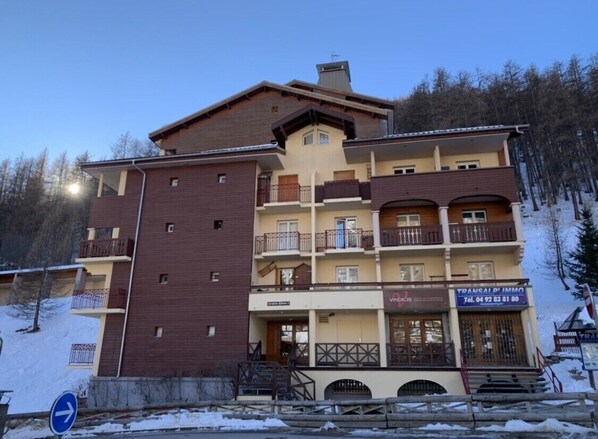 Un hôtel à plusieurs étages, doté de balcons, avec un télésiège visible au loin.