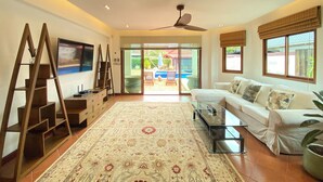 A spacious living room with a large sofa, a glass coffee table, and a wooden ladder. - Tropical 6 Bedroom Villa Sanctuary (Hua Hin)