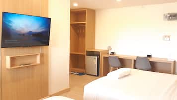 Habitación de hotel con cama, escritorio, silla, televisor y armario.
