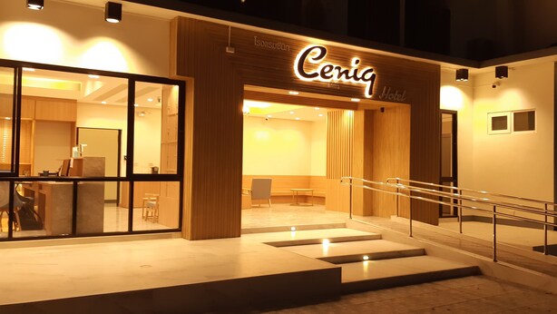 Exterior del Hotel Ceriq, con un diseño moderno, que presenta fachada de vidrio, una escalera con barandillas metálicas e iluminación interior cálida.