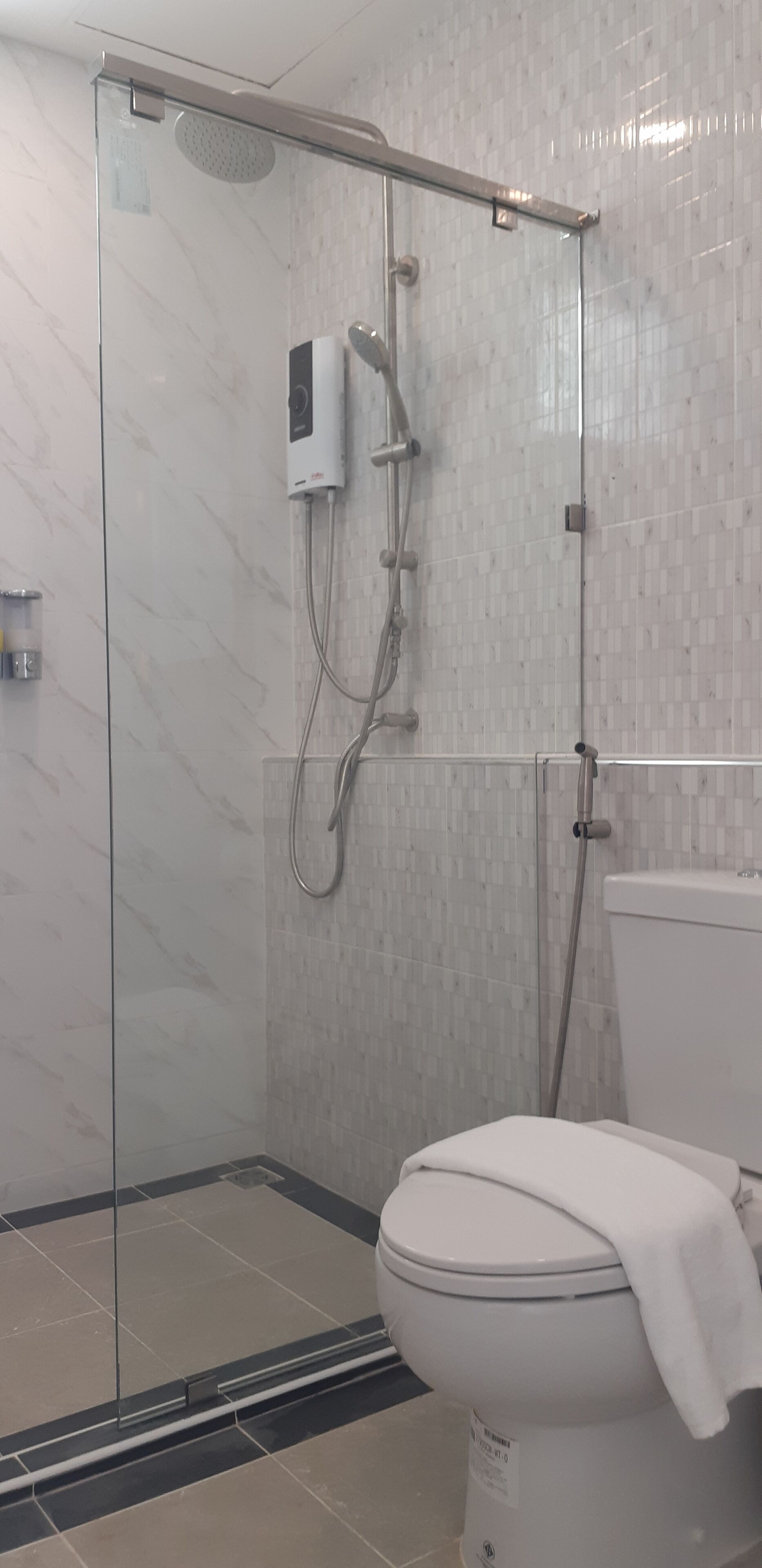 Ein modernes Badezimmer mit einer Duschkabine aus Glas, einer weißen Toilette und einer gefliesten Wand.