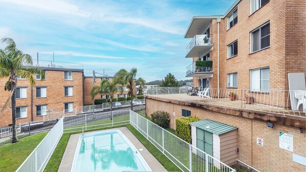 Un immeuble résidentiel doté d’une piscine, de balcons et d’une terrasse clôturée.