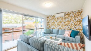 Relax in this stylish living room with a sofa set, coffee table, and flat-screen TV, offering a view of the surrounding area.