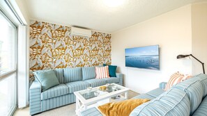 Relax in this inviting living room with a large window, striped sofa, and flat-screen TV.
