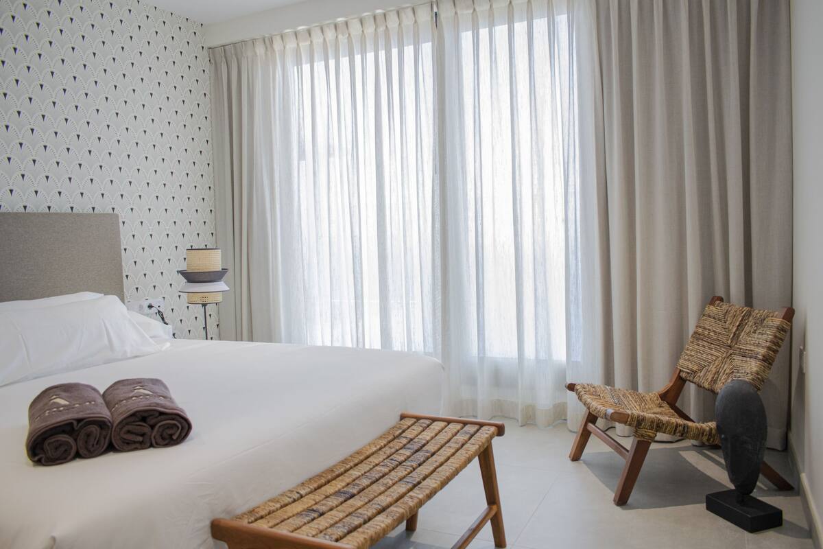 Une chambre d’hôtel avec un lit, un banc, une chaise et une lampe.