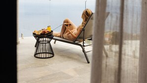 Un fauteuil de relaxation avec une petite table à proximité, donnant sur une étendue d’eau.