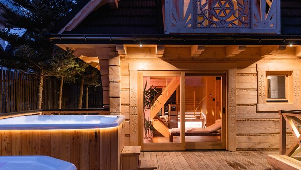 Una cabana de fusta amb una banyera d'hidromassatge, una escala que condueix a un dormitori i una finestra gran.