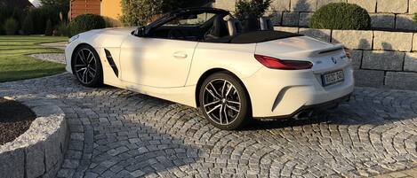 Um carro conversível branco estacionado em um caminho de pedras.