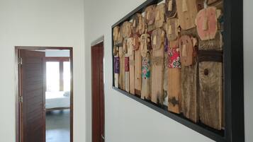 A hallway with a wooden wall art piece and a partially open door leading to a room.