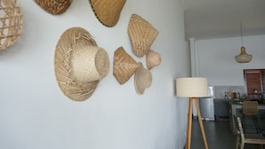 Ein Zimmer mit weißer Wand, verziert mit verschiedenen gewebten Körben, und einer Stehlampe.