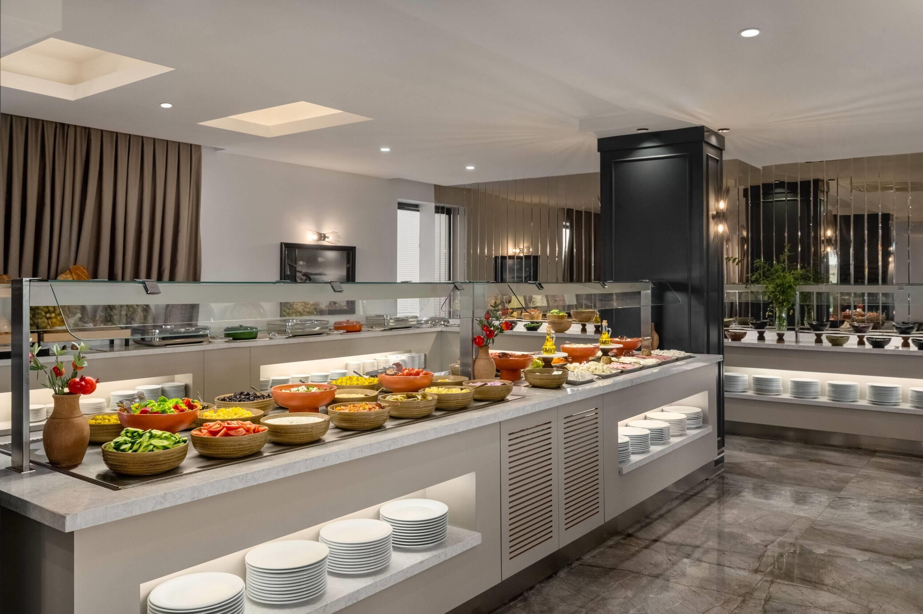 A modern hotel buffet with a variety of food options, a glass partition, and a contemporary interior design.