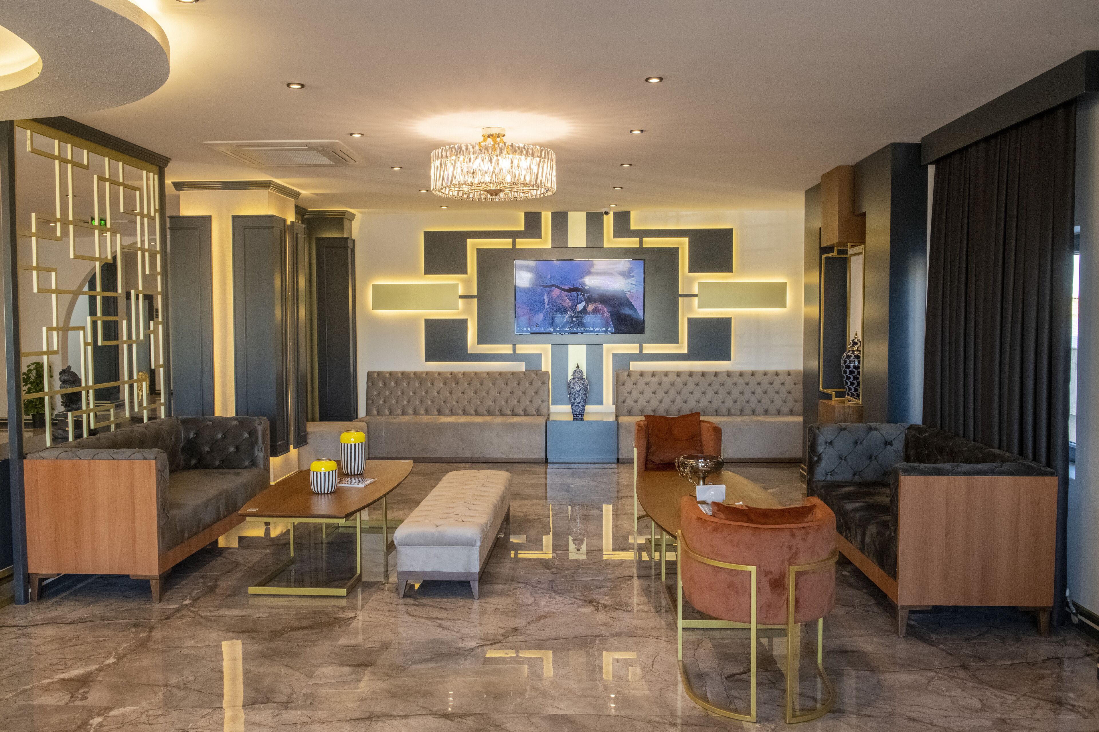 A modern living room with a large TV, comfortable seating, and a decorative wall panel.