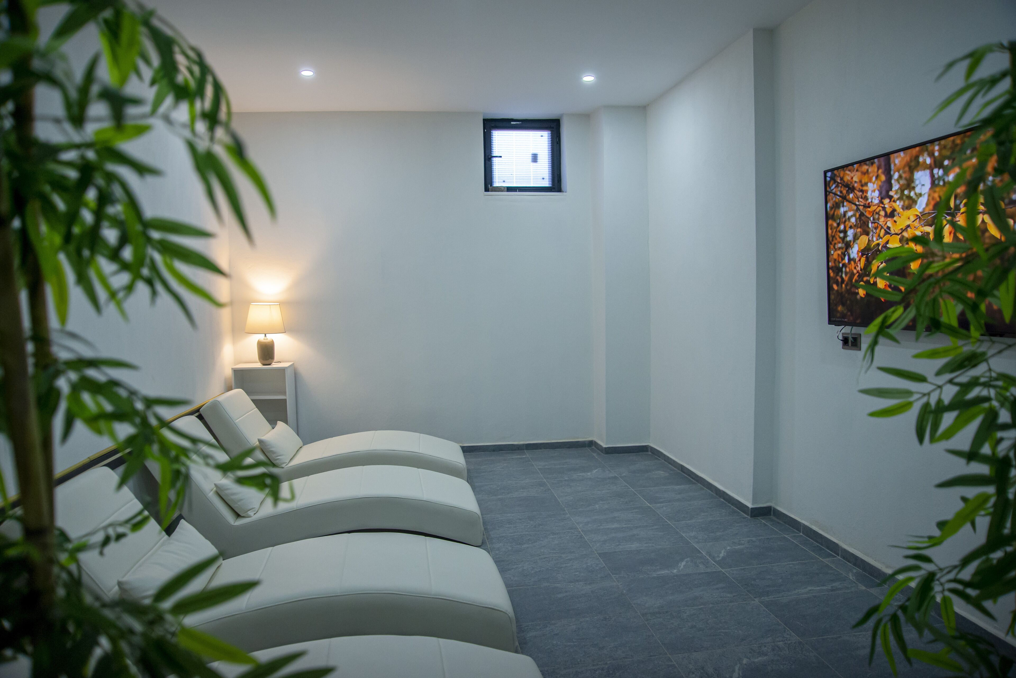 A spa room with a massage table, a wall-mounted TV, and a small window.