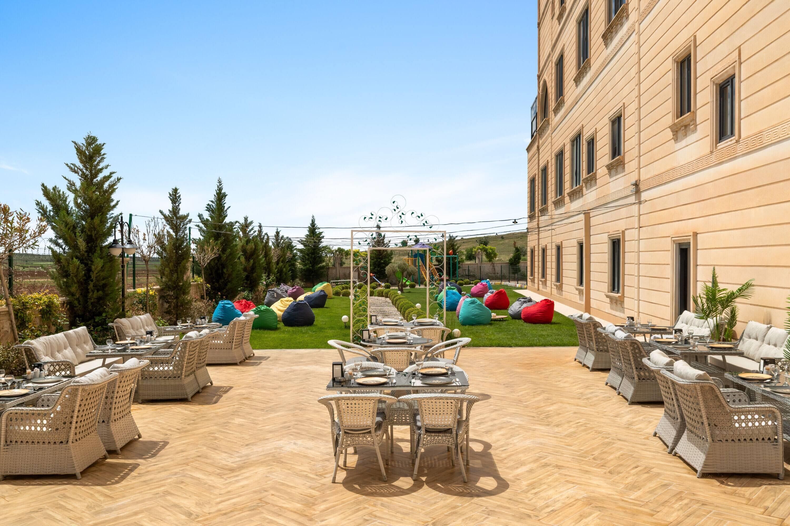 Eine Terrasse im Freien mit Korbmöbeln, einem Essbereich und bunten Sitzsäcken.