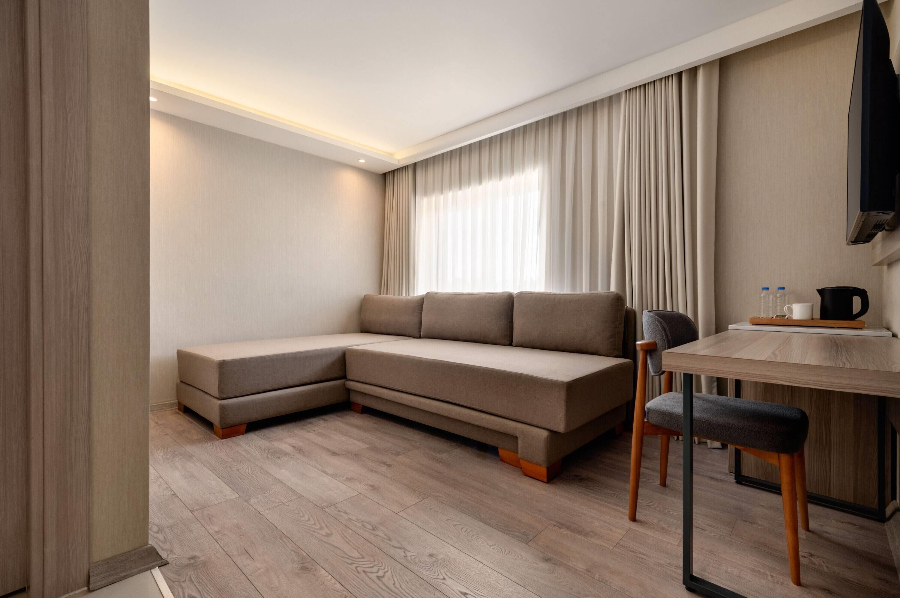 A modern living room with a sectional sofa, a dining table, and a TV mounted on the wall.