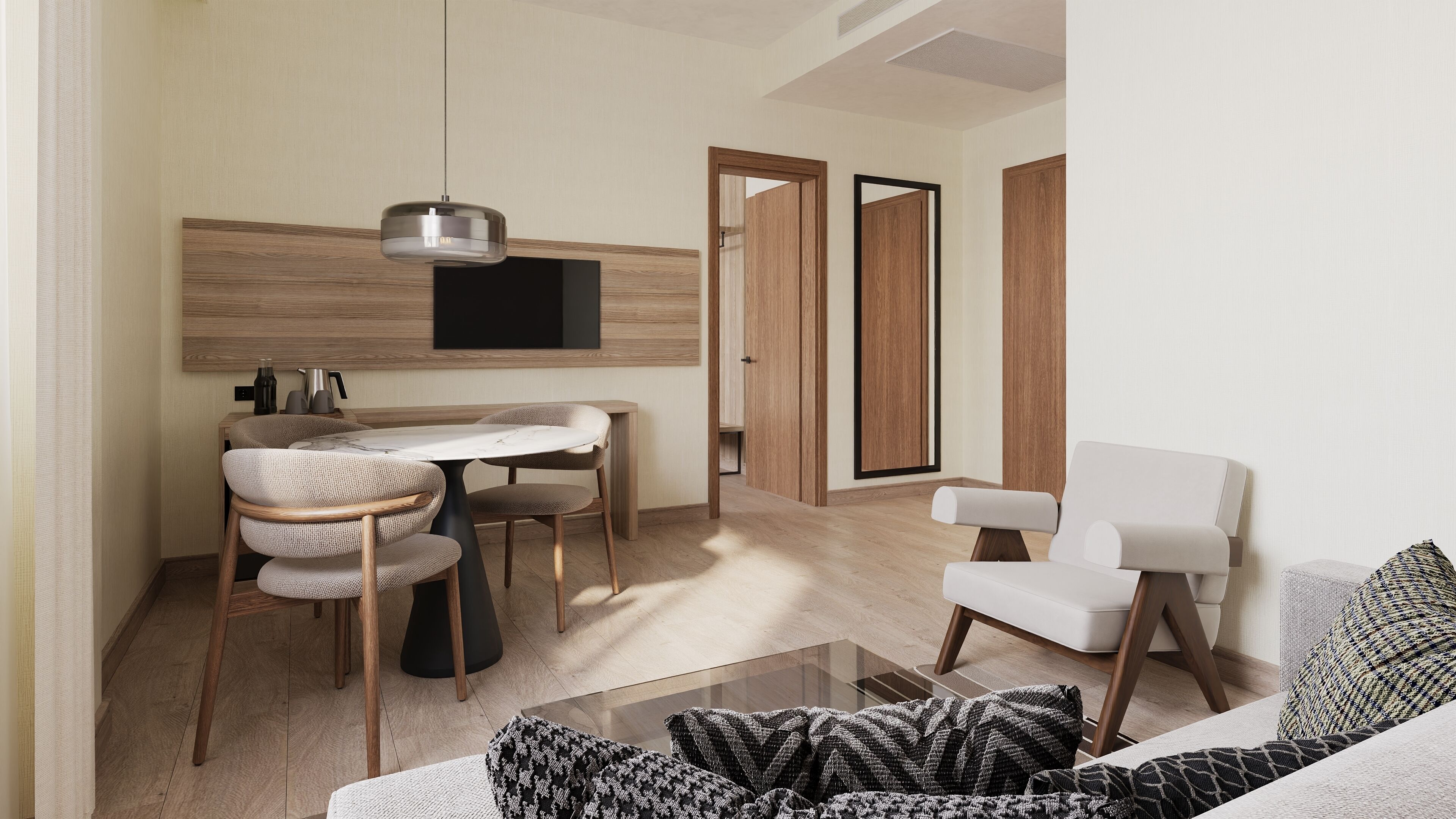 A modern living room with a dining area, a flat-screen TV mounted on the wall, and a sofa with patterned cushions.