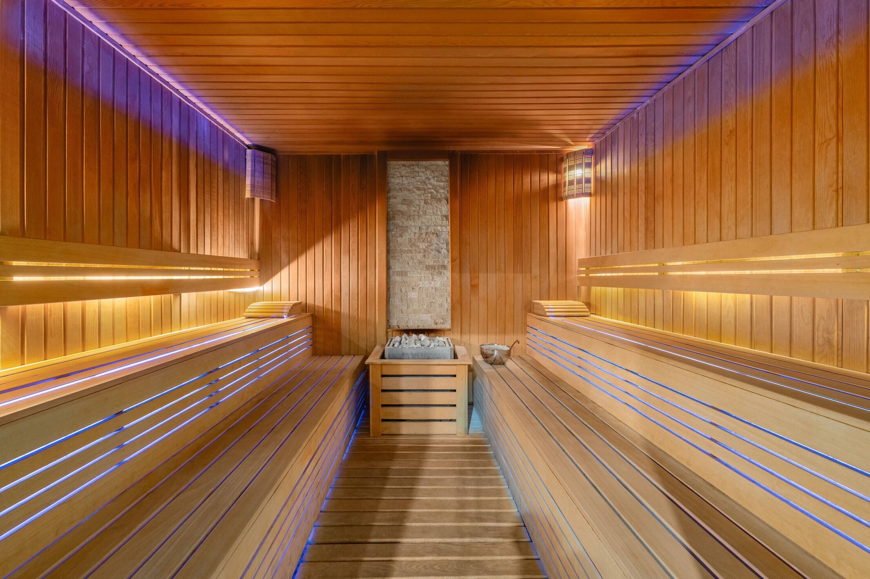Eine Sauna mit Holzbänken und einer zentralen Steinwand.