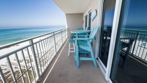 Ein Balkon mit Blick auf Strand und Meer. Türkisfarbene Stühle und ein Tisch sind vorhanden.