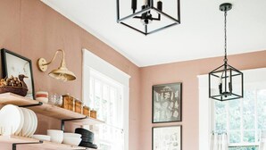 A kitchen with white cabinets, a stainless steel sink, and a hanging light fixture.
