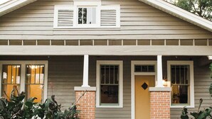 A two-story house with a front porch, brick pillars, and a small front yard.