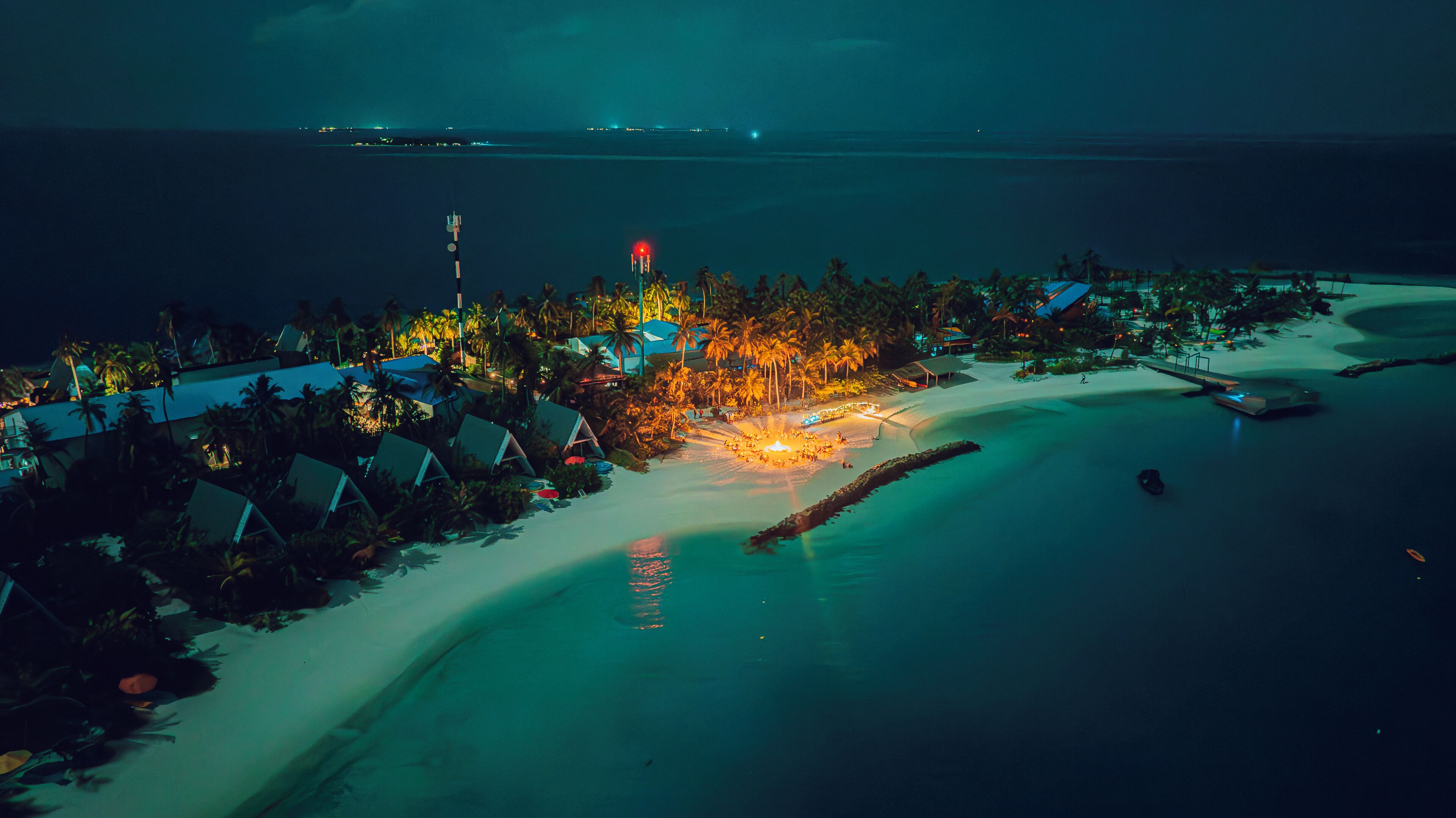 An aerial view of a resort with beachfront accommodations, a sandy beach, and a calm sea.