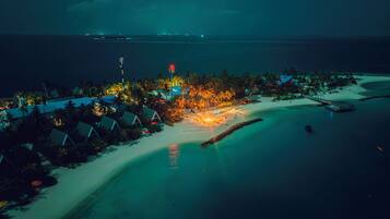 An aerial view of a resort with beachfront accommodations, a sandy beach, and a calm sea.