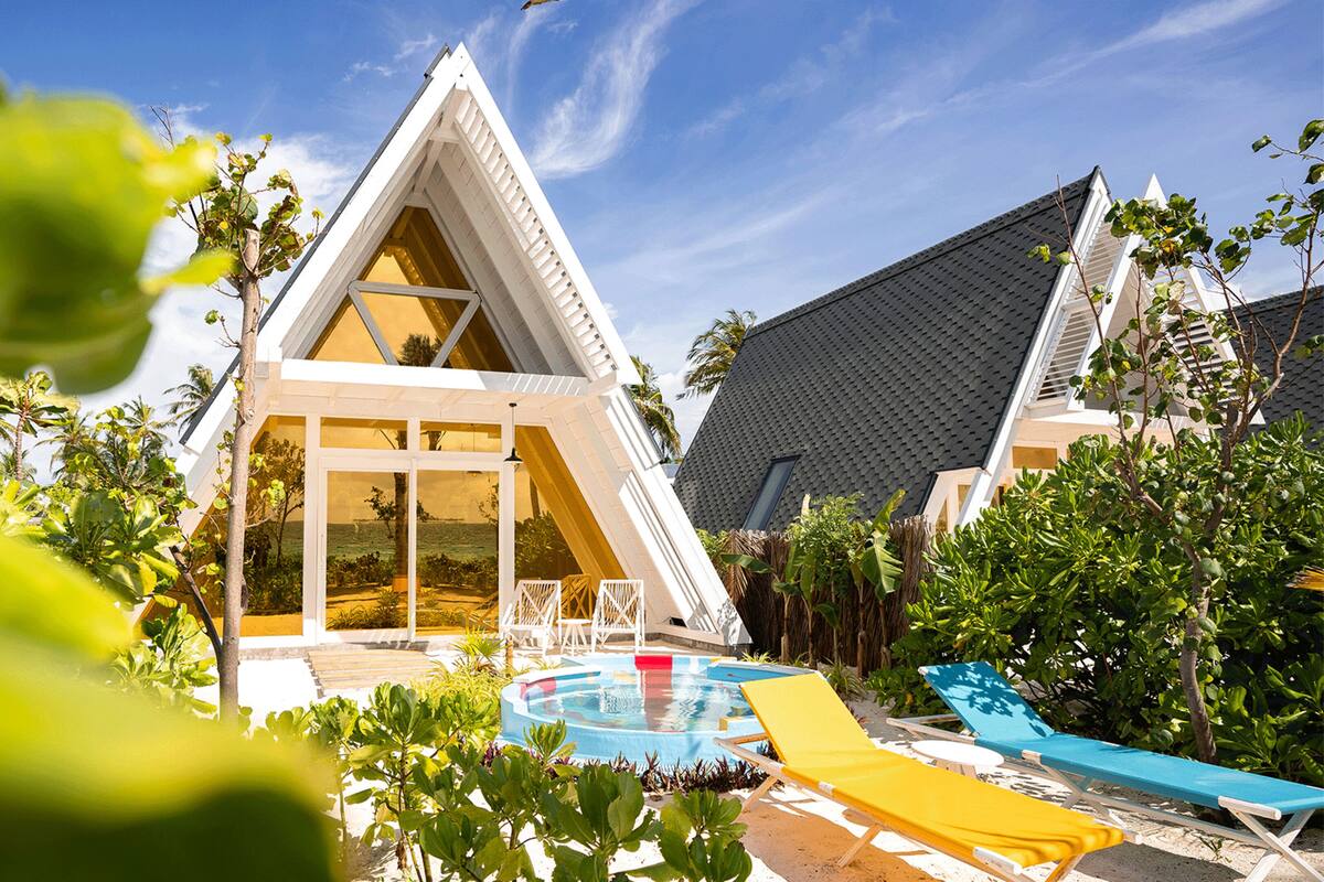 A modern villa with a triangular roof, a swimming pool, and outdoor seating.