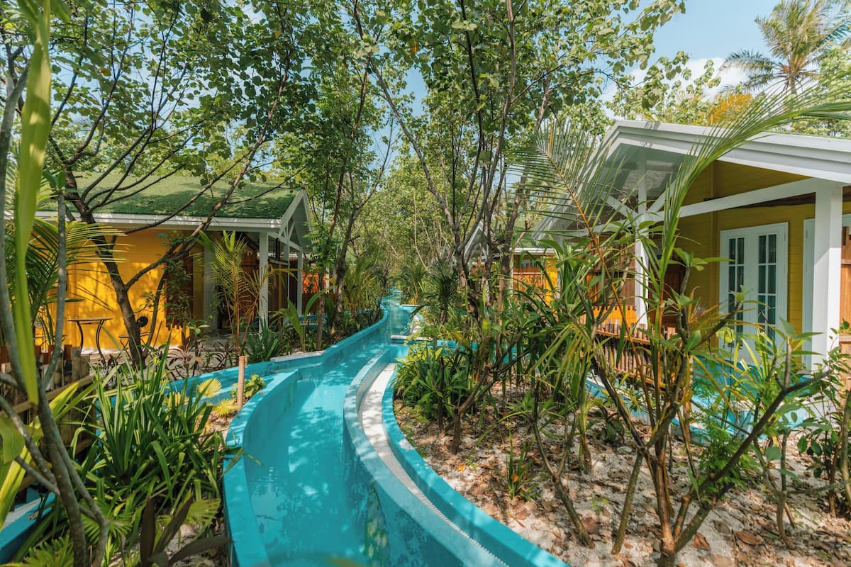 A pathway leading to a building surrounded by lush greenery and a pool.