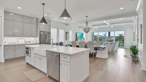 A modern kitchen with white cabinetry, a central island, and pendant lighting.