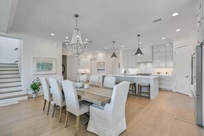 A modern kitchen with white cabinets, a central island, and pendant lighting.