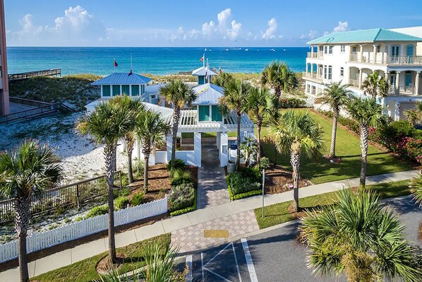 A coastal hotel with a beach view, palm trees, and a clear sky.