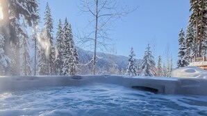 A hot tub surrounded by snow-covered trees and mountains.