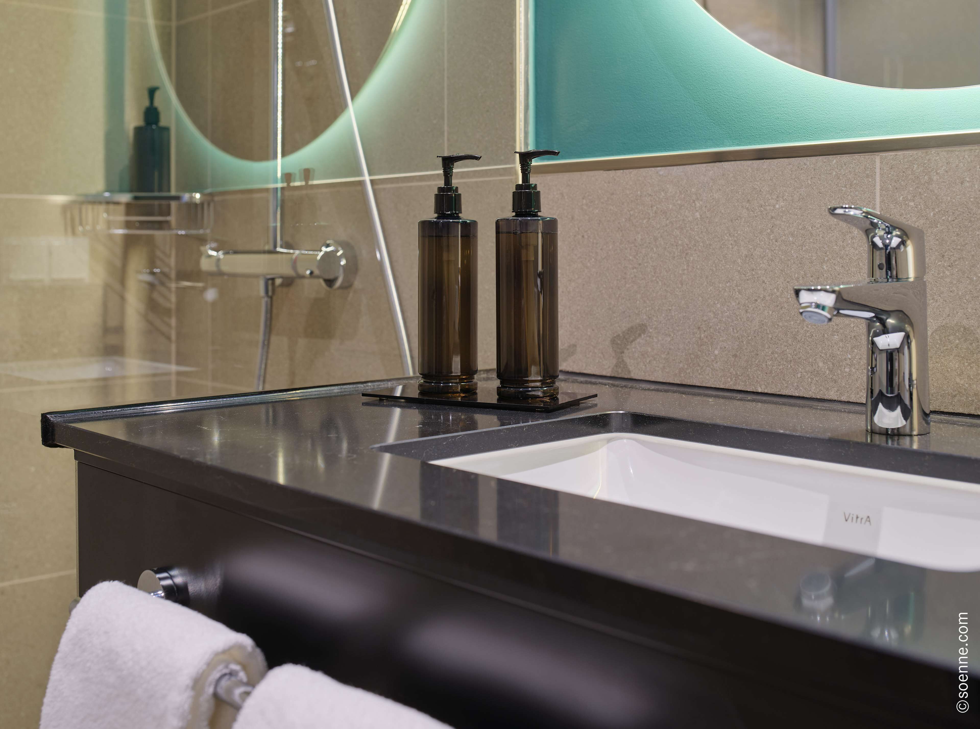 A modern bathroom with a black countertop, a white sink, and a mirror.