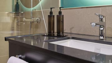 A modern bathroom with a black countertop, a white sink, and a mirror.