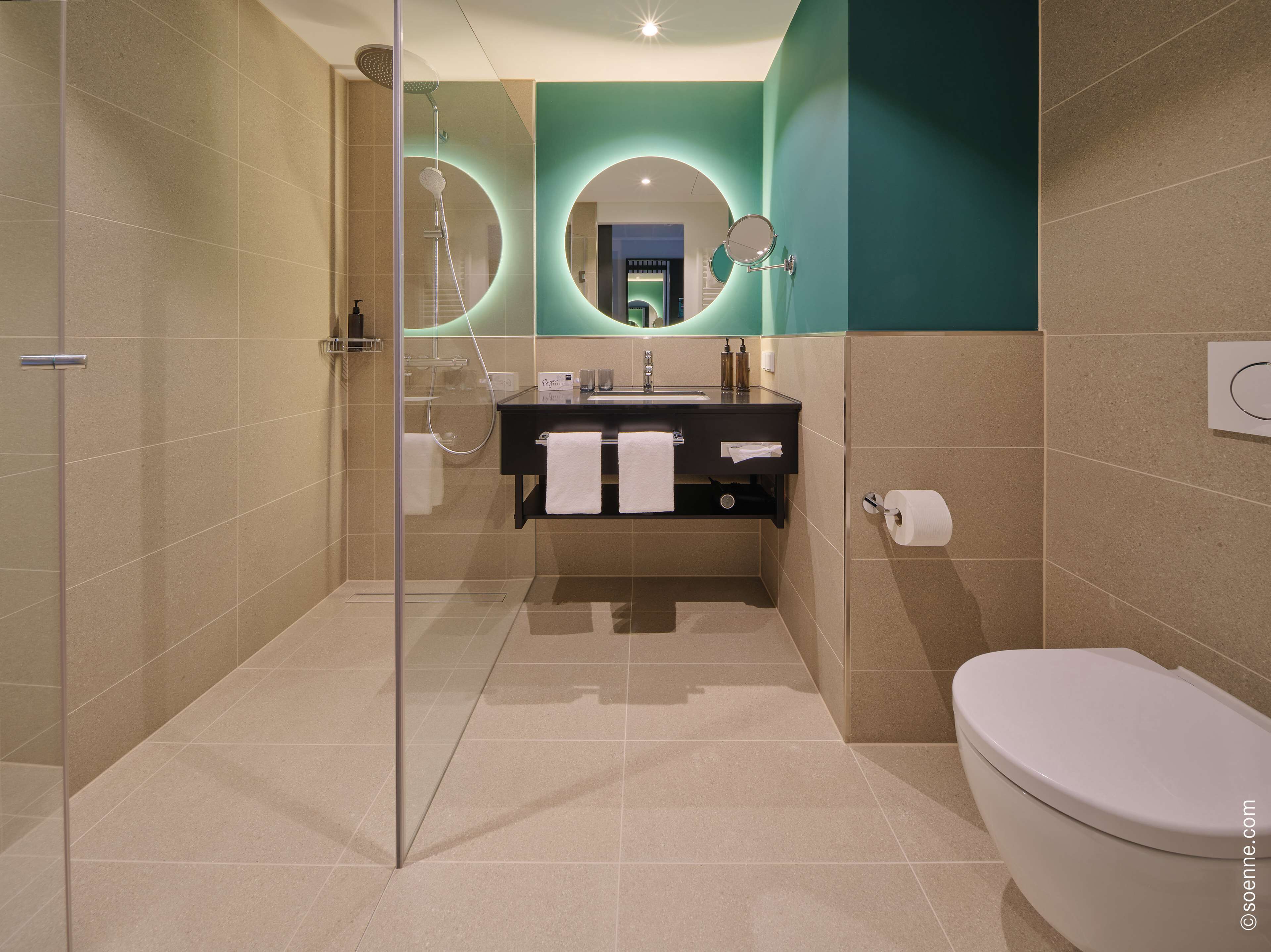 Une salle de bain moderne avec une douche à parois de verre, un lavabo avec un miroir et des toilettes.