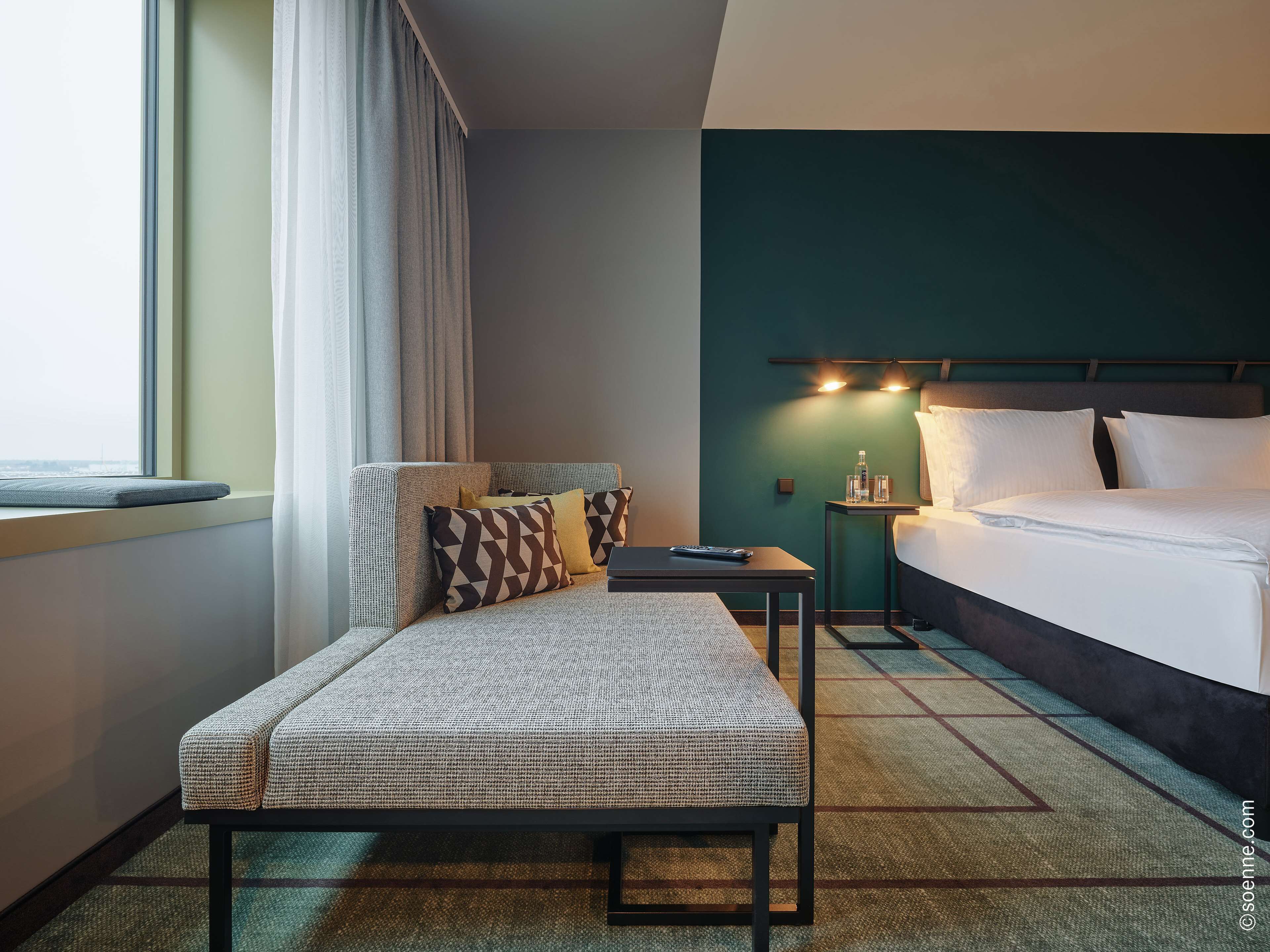 Una habitación de hotel con cama, sofá, una mesita y una mesilla de noche.