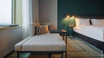 Una habitación de hotel con cama, sofá, una mesita y una mesilla de noche.