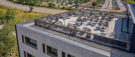 A rooftop terrace with outdoor seating and a view of a parking lot and fields.