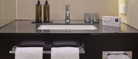 A modern bathroom with a large sink, two hand pumps, a mirror, and a towel rack.