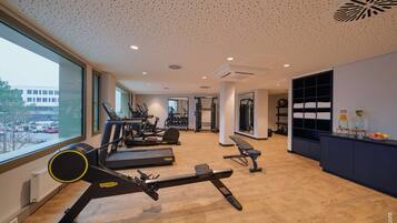 Un gimnasio moderno con cintas de correr, elípticas y equipamiento de pesas.