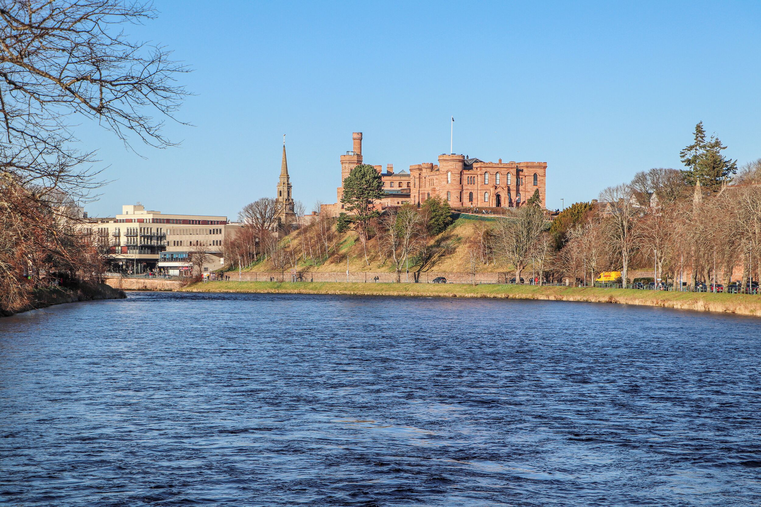 A historic building with a tower and a river in the foreground.
