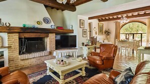 A cozy living room with a fireplace, leather armchair, and a dining area with a table and chairs. - San Martino, Certaldo, Florence and Chianti (Certaldo)