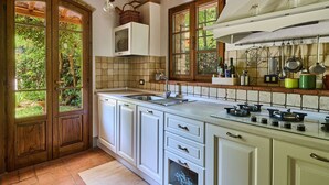 A kitchen with white cabinets, a built-in stove, and a window overlooking greenery. - San Martino, Certaldo, Florence and Chianti (Certaldo)