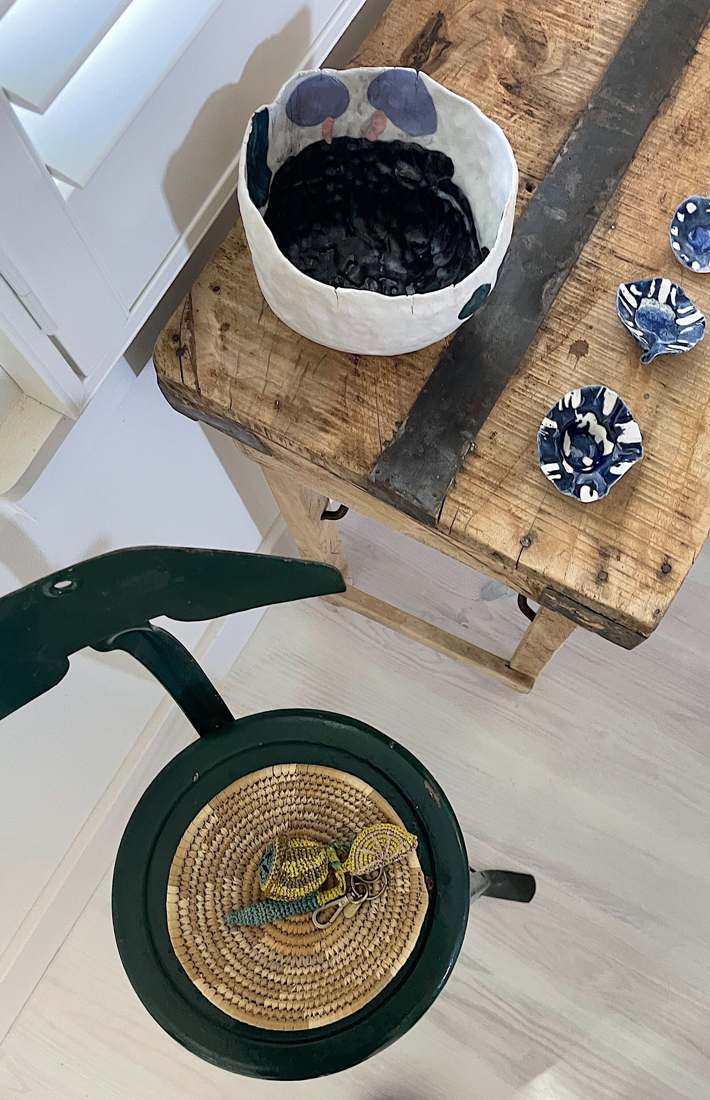 A wooden table with a woven basket, a bowl, and decorative plates.