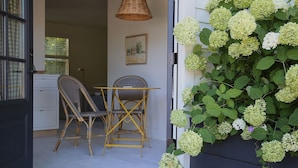 A room with a dining table and chairs, a hanging light fixture, and a wall-mounted plant with hydrangeas. - Boutique Studio in the Heart of Charlevoix (Charlevoix)