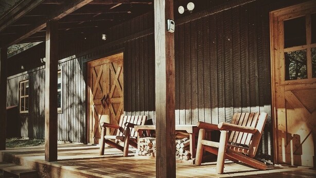 Een houten veranda met twee schommelstoelen en een schuurdeur.