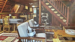 Een rustiek houten interieur met een eethoek, een wenteltrap en een gezellige zithoek.