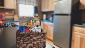 Een rieten mand op een aanrecht met een fles, koffieporties en een klein zakje.