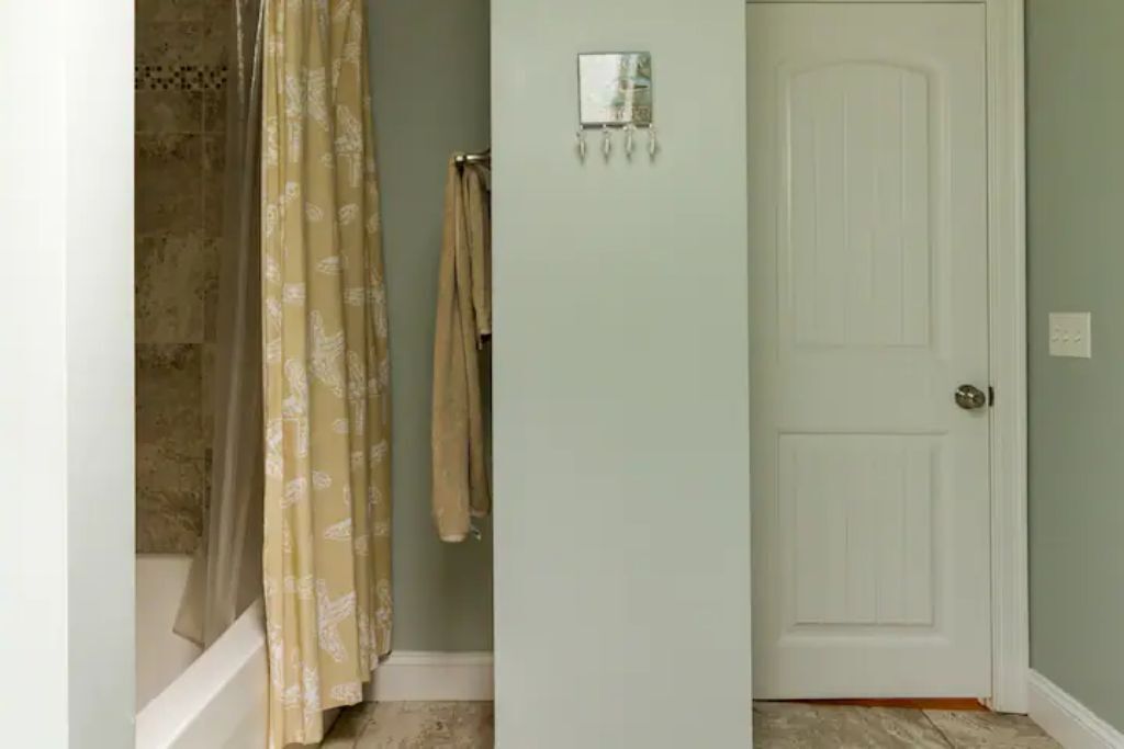 Une salle de bain avec une douche, un porte-serviettes et une porte.
