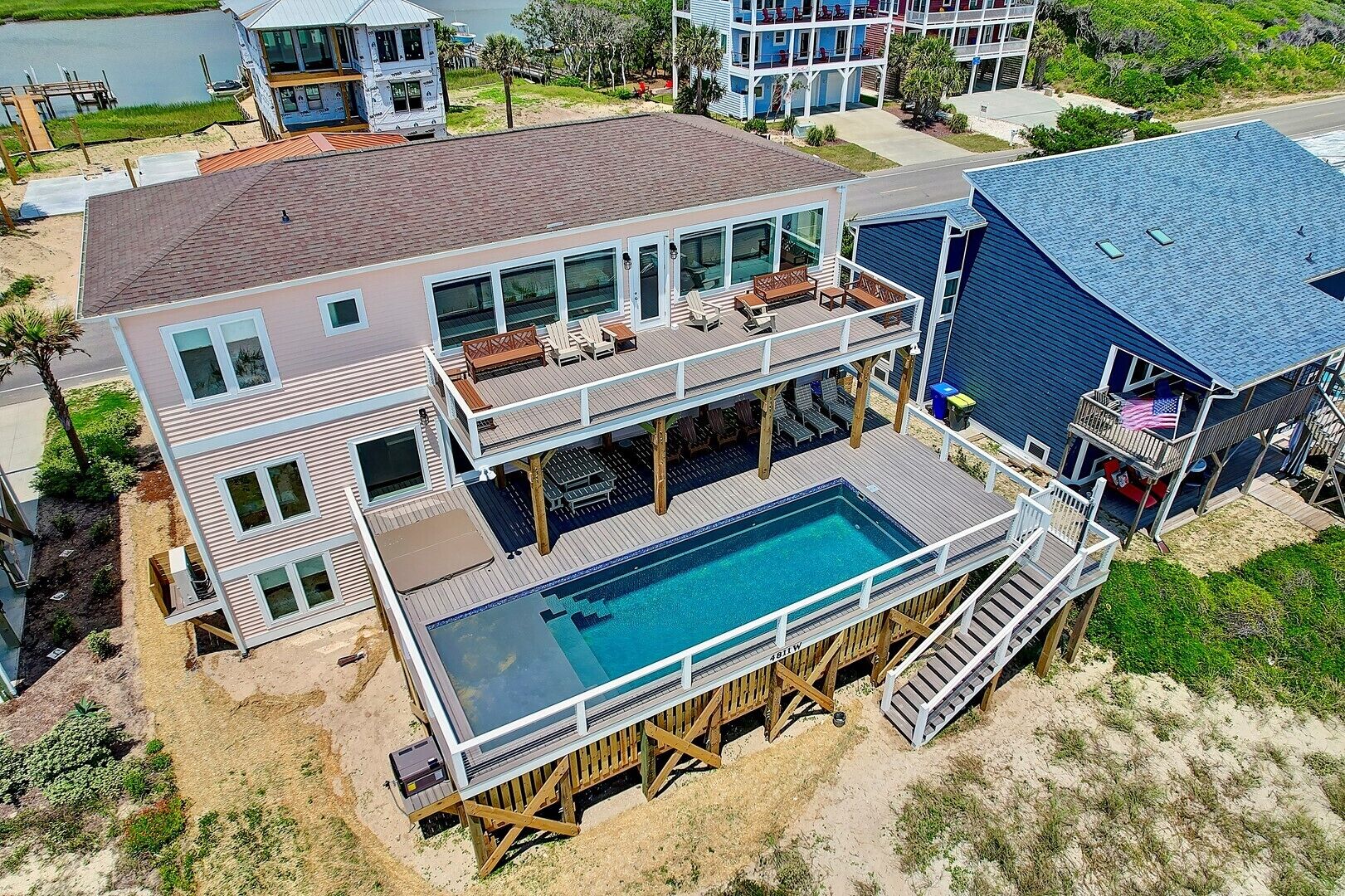 Una casa de varios pisos con una piscina grande, mobiliario exterior y una terraza.